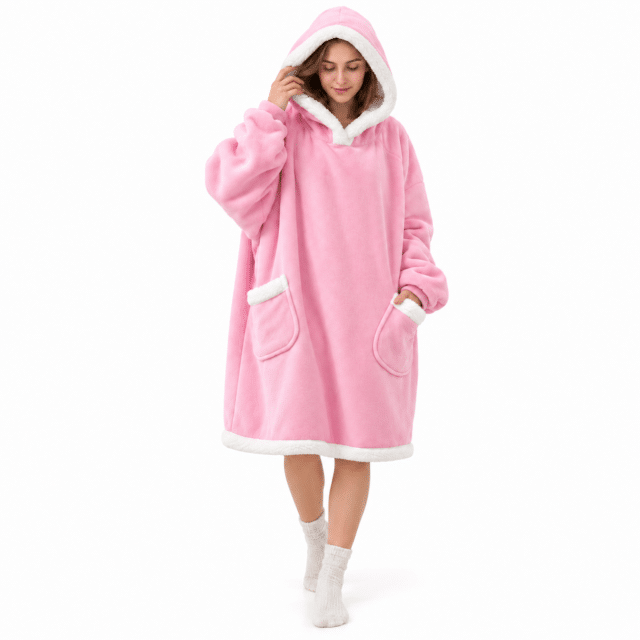 Vrouw met capuchon op in een lange roze Snuggle hoodie deken met twee teddy zakken