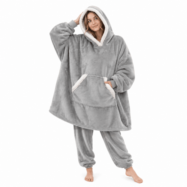 Vrouw met capuchon op in een lichtgrijze Snuggle hoodie deken met bijpassende pyjamabroek